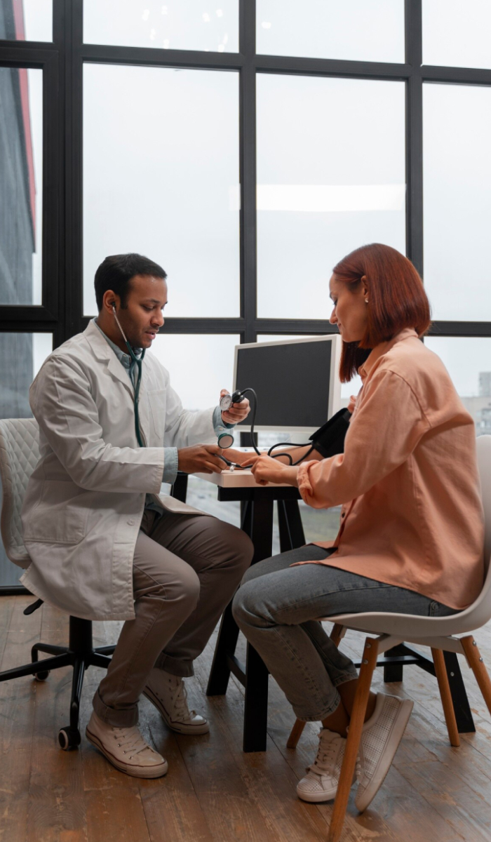 Doctor conducting clinical supervision while demonstrating blood pressure monitoring techniques to a patient during a healthcare consultation.