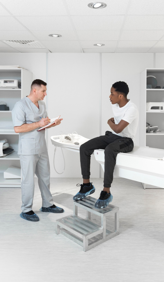 Healthcare professional providing clinical supervision and discussing patient assessment with a young adult during a medical consultation.
