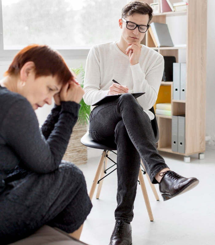 Psychological assessments session with a therapist taking notes while a distressed client discusses their mental health concerns.