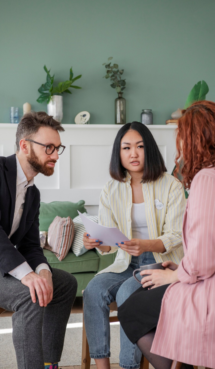 Psychological assessments in a group therapy setting where a psychologist facilitates discussion with multiple participants.